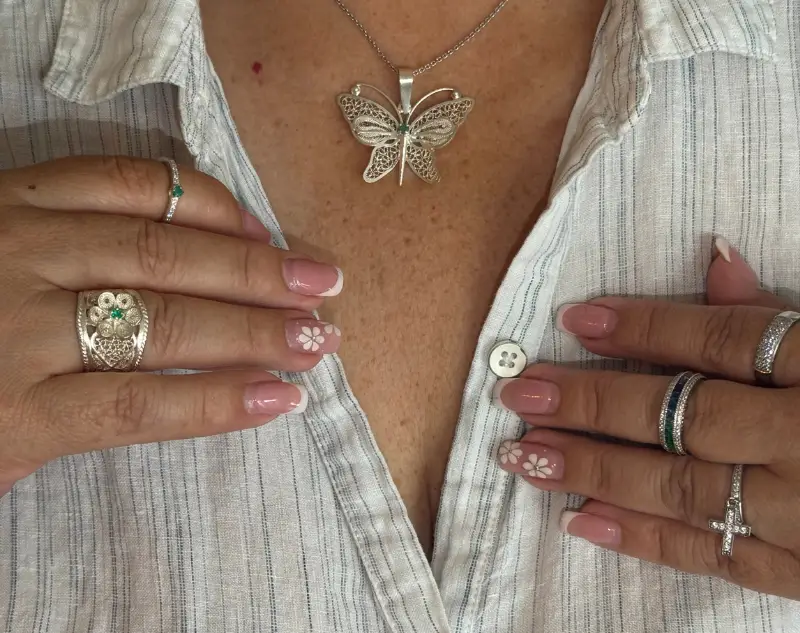 Modelo luciendo cllar de oro y anillos de oro y esmeralda arreglandoce la camisa