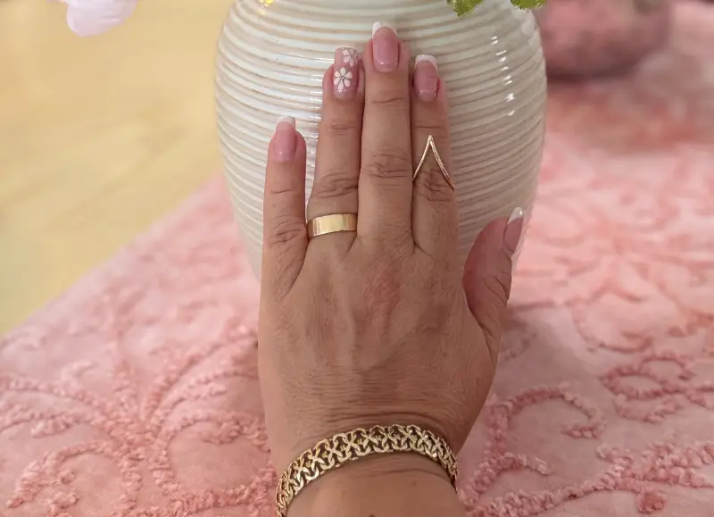 Modelo con anillos y pulsera Modelo luciendo anillos de oro de 14k con fondo rosado