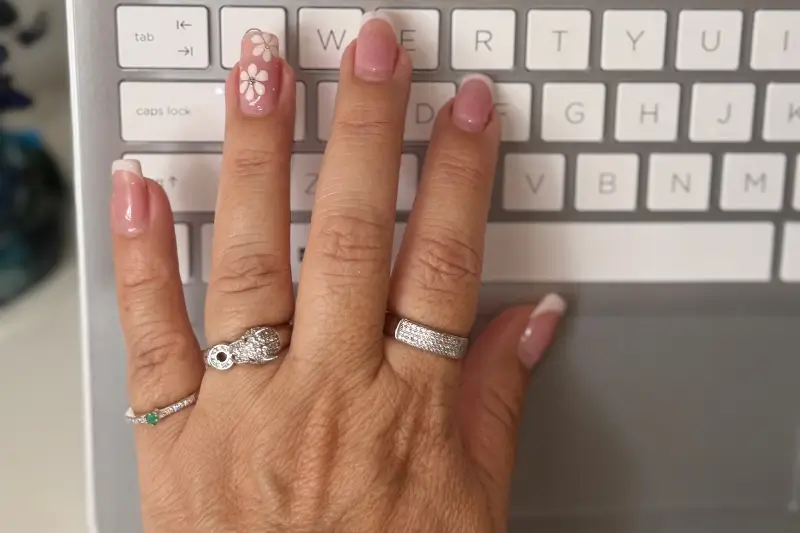 Modelo con anillos en computador Modelo simulando escribir en computador con anillos de oro
